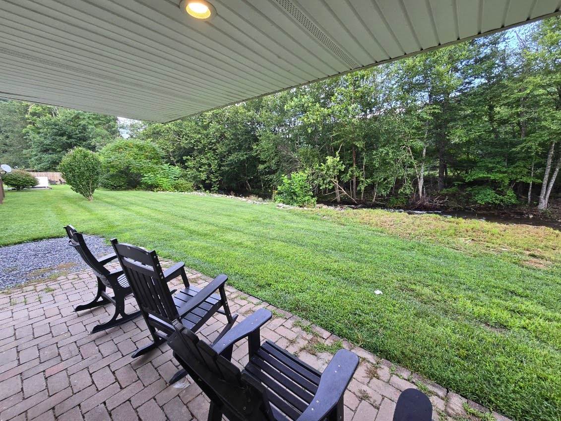 Covered back porch with rocking chairs overlooking the lawn and creek.