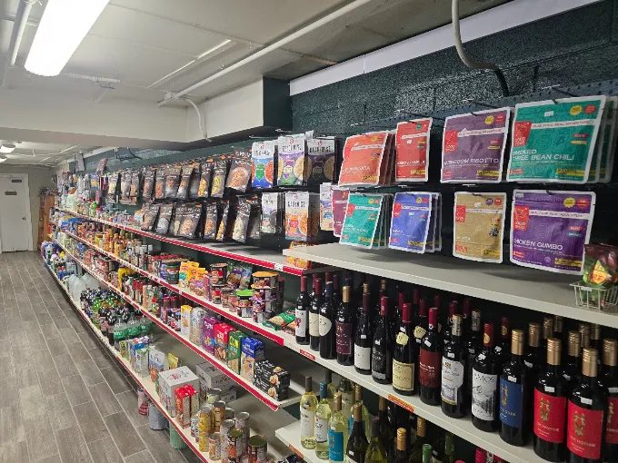 Inside the store: grocery aisle with snacks, camping meals, and a wine selection.